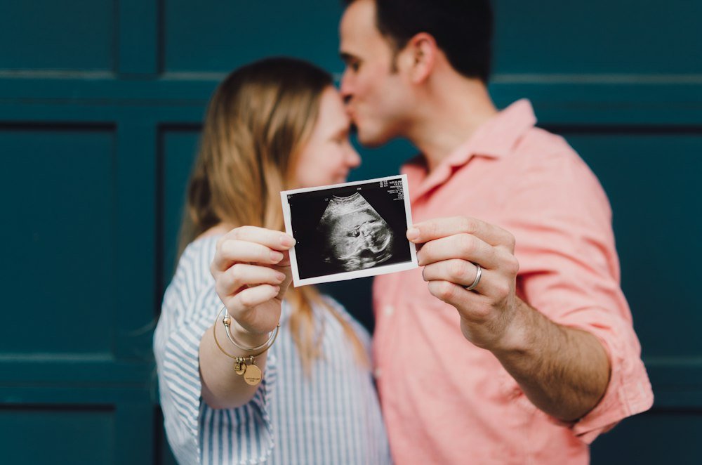 A couple holding up their baby's ultrasound photo